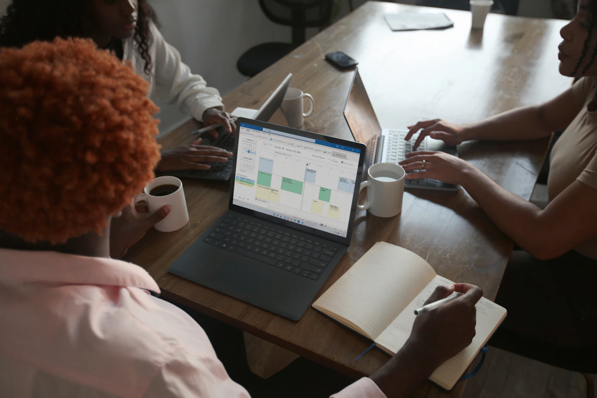 Three colleagues reviewing a schedule together at a meeting table.